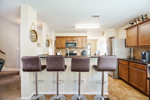 kitchen featuring backsplash, a kitchen bar, light tile patterned floors, and an island with sink