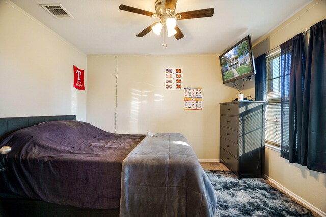 carpeted bedroom featuring ceiling fan and crown molding