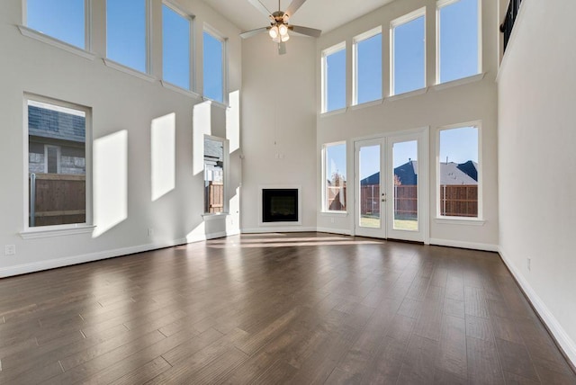 unfurnished living room featuring dark hardwood / wood-style floors, ceiling fan, a high ceiling, and french doors