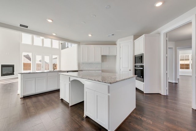2438 Meridian Pl, Midlothian, TX 76065 - kitchen with a sink, a center island, oven, dark wood-type flooring, and light stone countertops