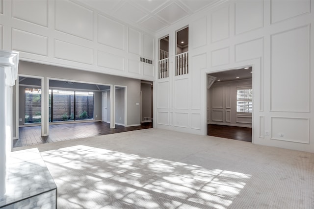 unfurnished living room featuring a towering ceiling, hardwood / wood-style flooring, and a healthy amount of sunlight