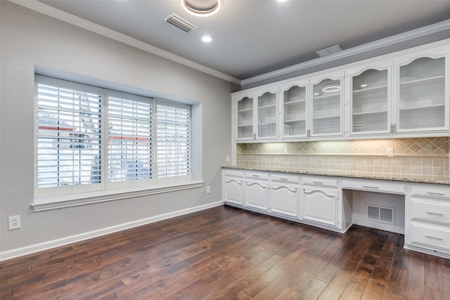 interior space featuring crown molding, built in desk, and dark wood-type flooring