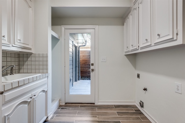 laundry room featuring electric dryer hookup, cabinets, sink, and dark wood-type flooring