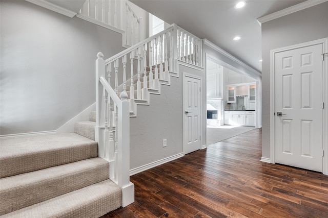 staircase with hardwood / wood-style floors, sink, and crown molding