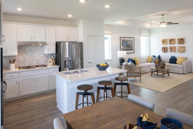 kitchen with white cabinetry, sink, stainless steel appliances, dark hardwood / wood-style flooring, and a kitchen island with sink