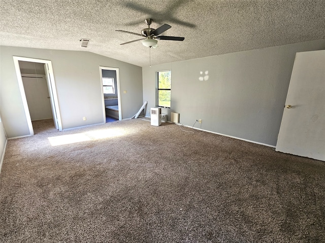 unfurnished bedroom featuring carpet, lofted ceiling, a walk in closet, ceiling fan, and a closet