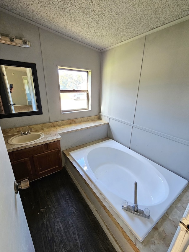 bathroom with hardwood / wood-style floors, vanity, a bath, and a textured ceiling