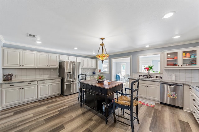 5795 Spillane St, Nevada, TX 75173 - kitchen featuring appliances with stainless steel finishes, tasteful backsplash, hardwood / wood-style floors, white cabinetry, and hanging light fixtures