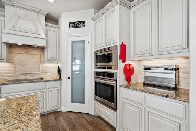 kitchen featuring appliances with stainless steel finishes, backsplash, stone countertops, white cabinets, and dark hardwood / wood-style floors