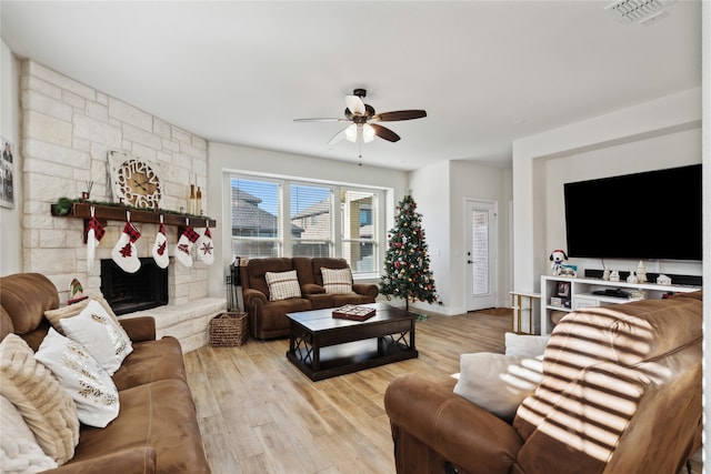 living room featuring a fireplace, light hardwood / wood-style flooring, and ceiling fan