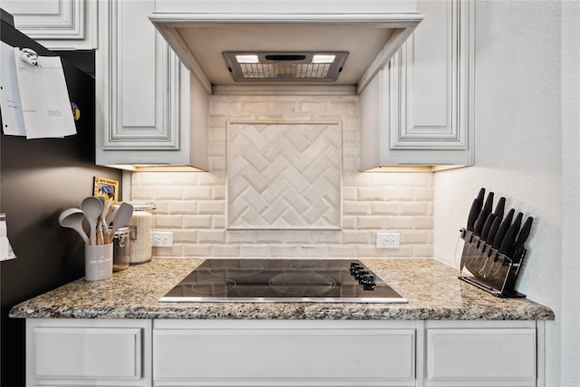 kitchen featuring white cabinets, stone countertops, black electric cooktop, and tasteful backsplash