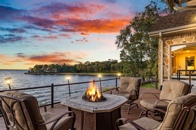 deck at dusk featuring a water view and a fire pit