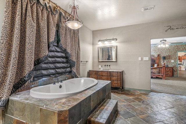 bathroom featuring tiled bath, ceiling fan, and vanity