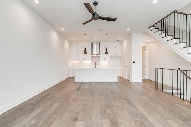 unfurnished living room with ceiling fan, light hardwood / wood-style floors, and sink