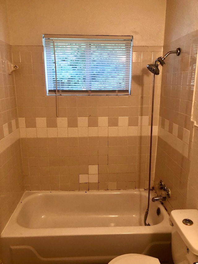 bathroom featuring tiled shower / bath and toilet