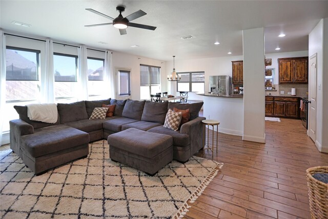 living room featuring a wealth of natural light, light hardwood / wood-style flooring, and ceiling fan with notable chandelier