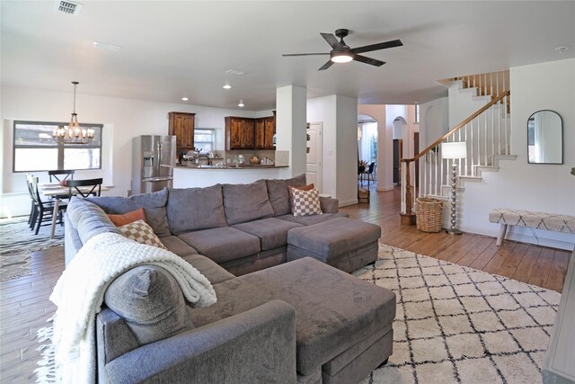 living room with ceiling fan with notable chandelier and light hardwood / wood-style floors