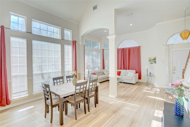 dining room with hardwood / wood-style floors, crown molding, and high vaulted ceiling