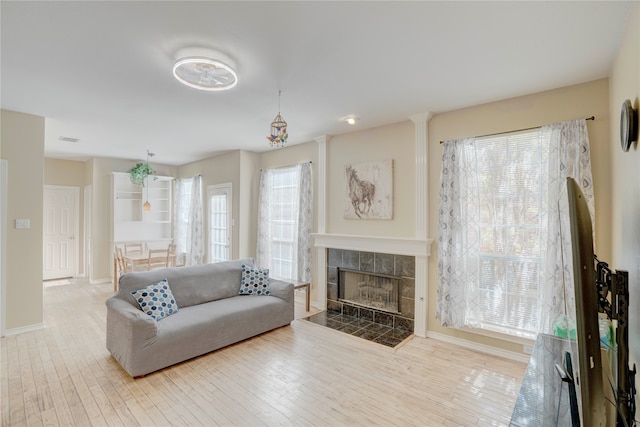 living room with a tile fireplace, hardwood / wood-style floors, and a healthy amount of sunlight