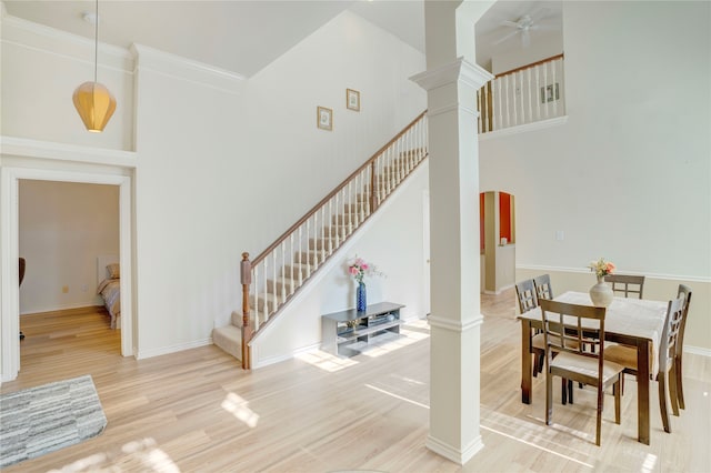 dining room with a high ceiling, light hardwood / wood-style floors, decorative columns, and crown molding