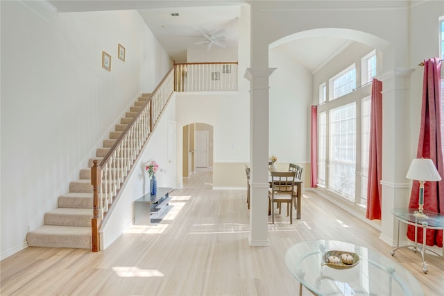 foyer featuring ceiling fan, a high ceiling, decorative columns, crown molding, and light hardwood / wood-style floors