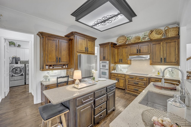 2405 Deer Run Ct, Heath, TX 75032 - kitchen featuring washing machine and clothes dryer, appliances with stainless steel finishes, light stone countertops, under cabinet range hood, and dark wood finished floors
