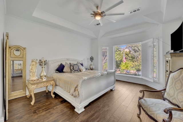 bedroom featuring a raised ceiling, crown molding, ceiling fan, and dark wood-type flooring