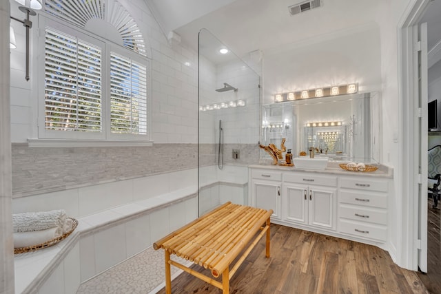 bathroom with crown molding, hardwood / wood-style floors, tiled shower, decorative backsplash, and vanity