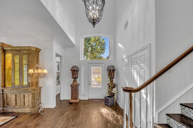 entryway featuring a high ceiling, hardwood / wood-style flooring, and an inviting chandelier