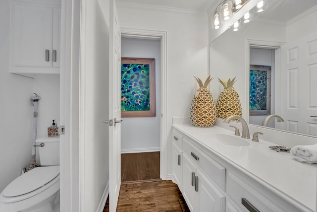 bathroom featuring toilet, vanity, ornamental molding, and hardwood / wood-style flooring