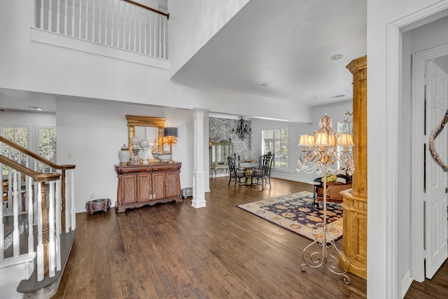 foyer featuring dark wood-type flooring, a wealth of natural light, and decorative columns