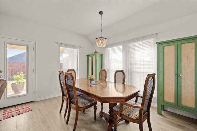 dining area with light hardwood / wood-style flooring, lofted ceiling, and a notable chandelier