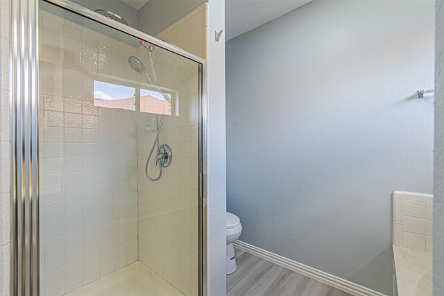 bathroom featuring walk in shower, wood-type flooring, and toilet