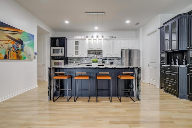 kitchen featuring white cabinets, decorative backsplash, stainless steel appliances, and a kitchen island