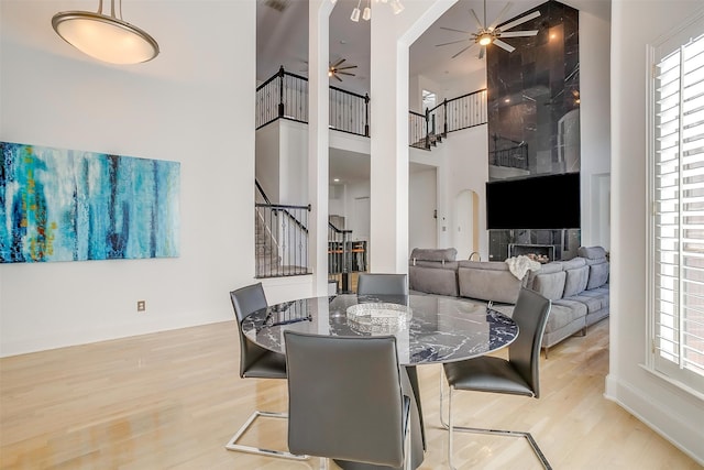 dining area with a wealth of natural light, a towering ceiling, and light wood-type flooring