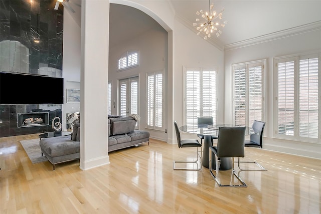 dining area with plenty of natural light, light hardwood / wood-style floors, crown molding, and high vaulted ceiling