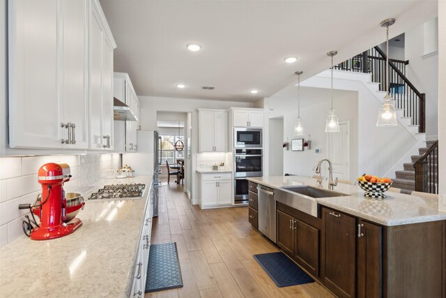 kitchen with stainless steel appliances, a fireplace, a sink, and white cabinets