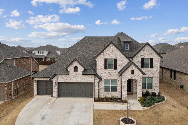 french provincial home featuring concrete driveway, brick siding, a front lawn, and a shingled roof