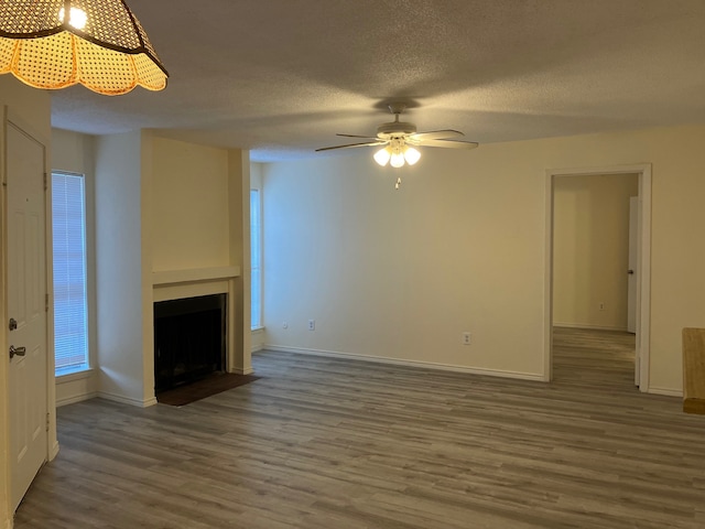 unfurnished living room featuring dark hardwood / wood-style floors, ceiling fan, and a textured ceiling