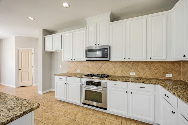 kitchen with white cabinetry, backsplash, dark stone counters, light tile patterned floors, and appliances with stainless steel finishes