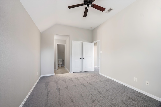 unfurnished bedroom with ensuite bath, ceiling fan, light colored carpet, and vaulted ceiling