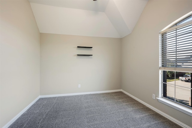 carpeted empty room featuring vaulted ceiling