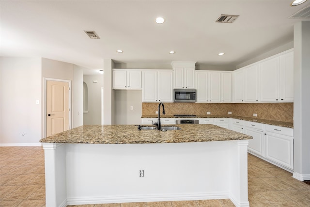 kitchen featuring a center island with sink, stone countertops, white cabinetry, and sink