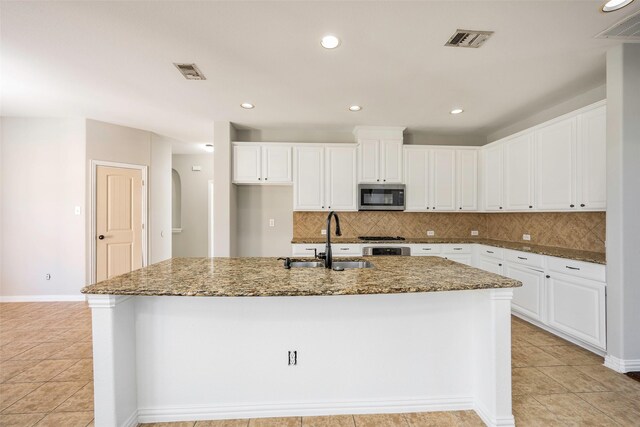 2280 Riviera Dr, Little Elm, TX 75068 - kitchen featuring stainless steel microwave, a sink, white cabinets, backsplash, and dark stone countertops