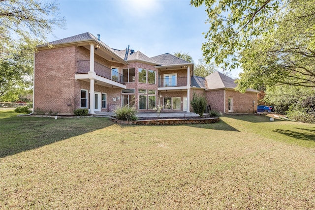 back of property with a lawn, a balcony, and a patio