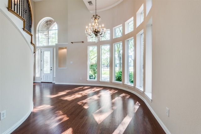 foyer entrance with a chandelier, a towering ceiling, and dark hardwood / wood-style flooring