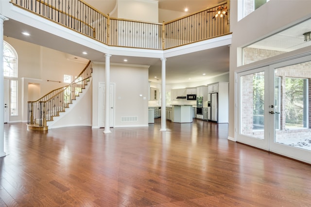 unfurnished living room with a high ceiling, a healthy amount of sunlight, and wood-type flooring