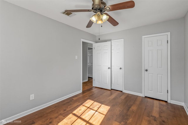 unfurnished bedroom featuring ceiling fan, a closet, and dark wood-type flooring