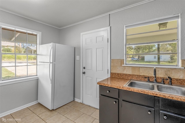 kitchen featuring light tile patterned floors, sink, crown molding, and white refrigerator