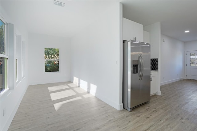 kitchen featuring light hardwood / wood-style floors, white cabinetry, stainless steel fridge with ice dispenser, and a healthy amount of sunlight